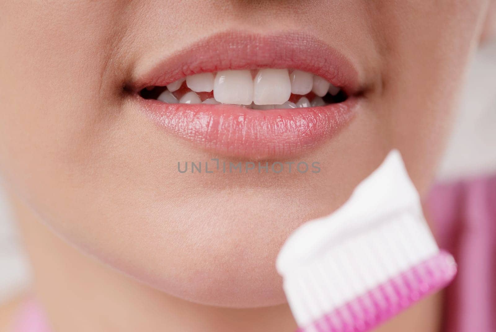 Close-up of a young woman with a toothbrush in front of her mouth