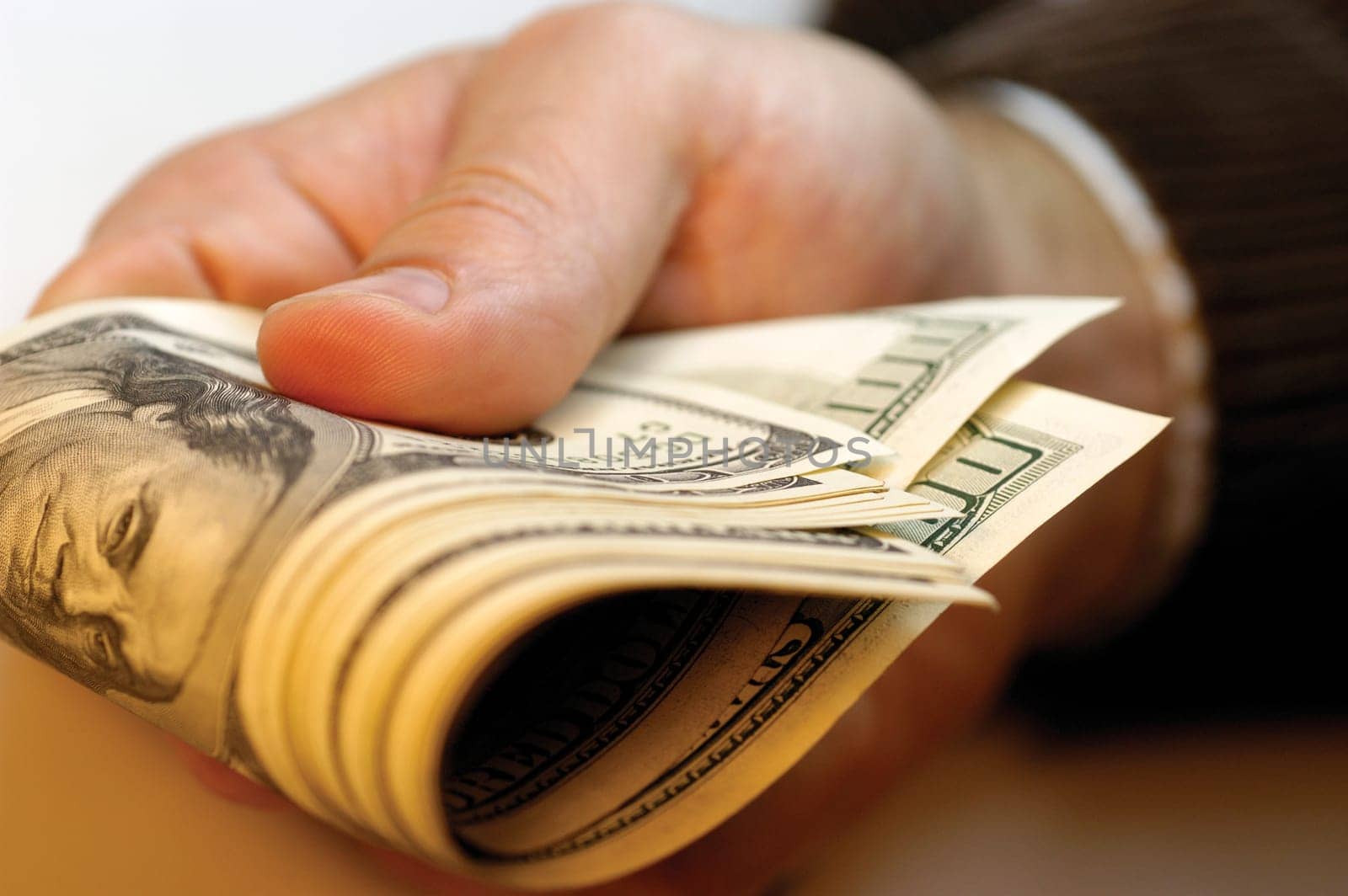 Businessman holding United States one hundred dollar bills, close-up