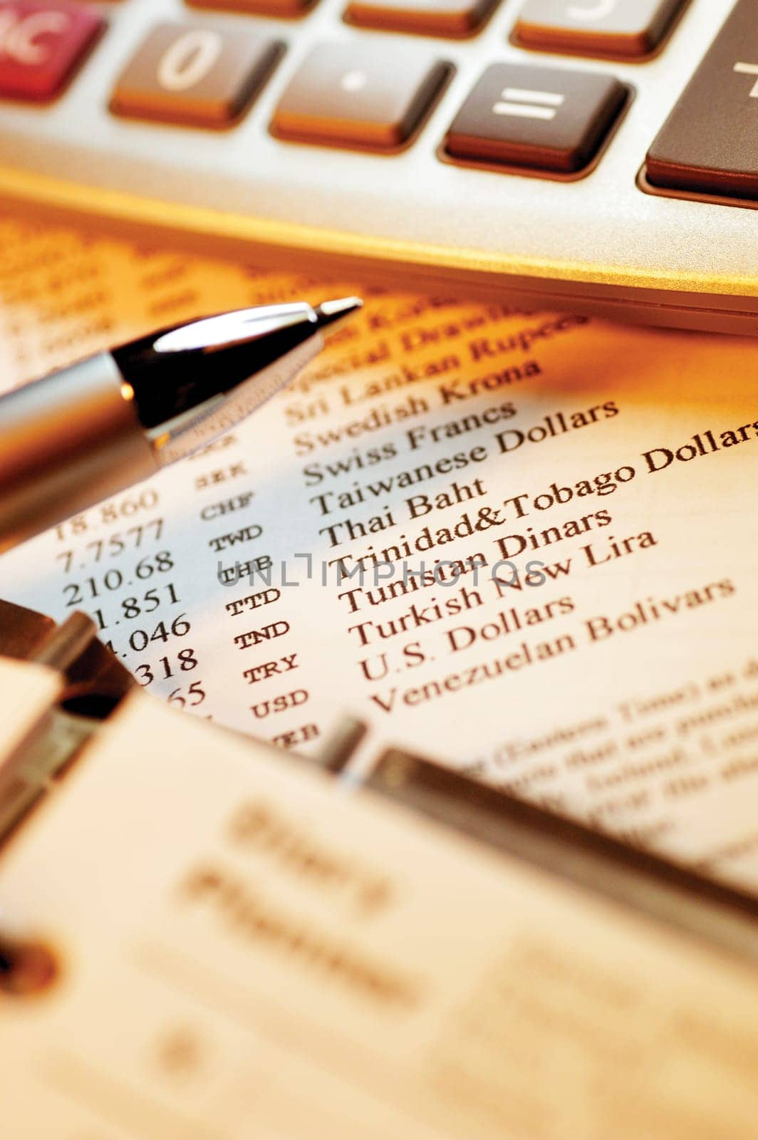 Calculator and pen on top of currency exchange rate information, close-up