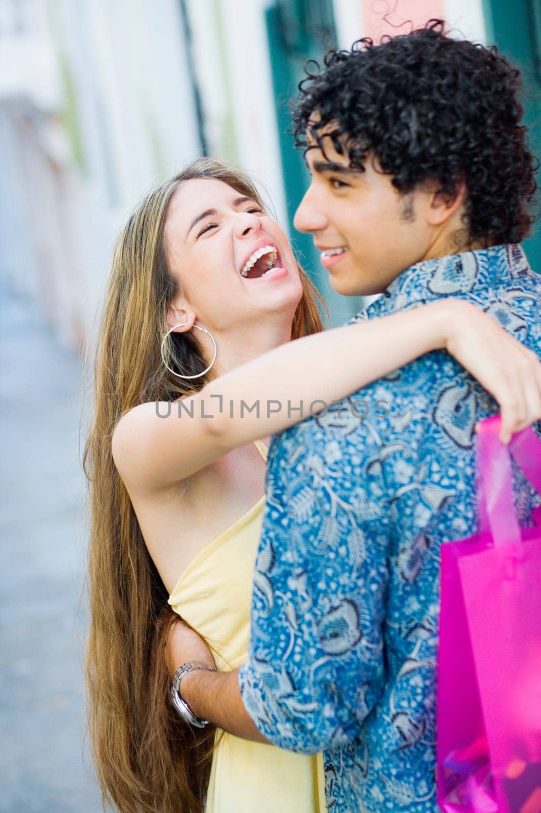 Close-up of a teenage girl embracing a young man and laughing