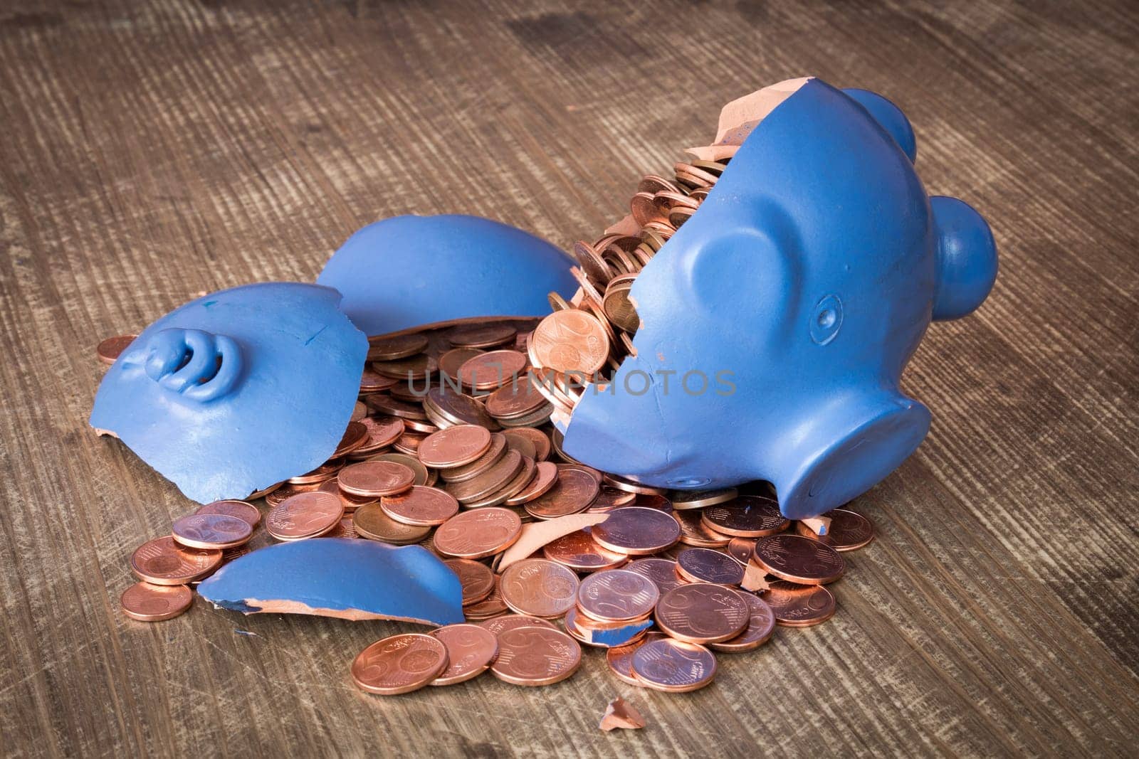 Broken piggy bank with coins scattered on the table