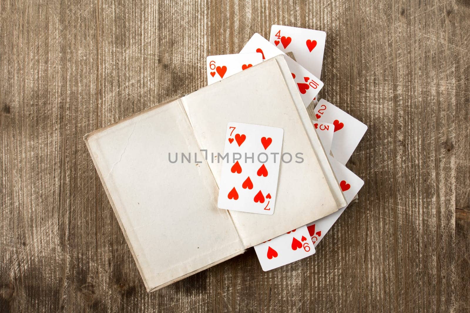 Open book and playing cards on wooden background