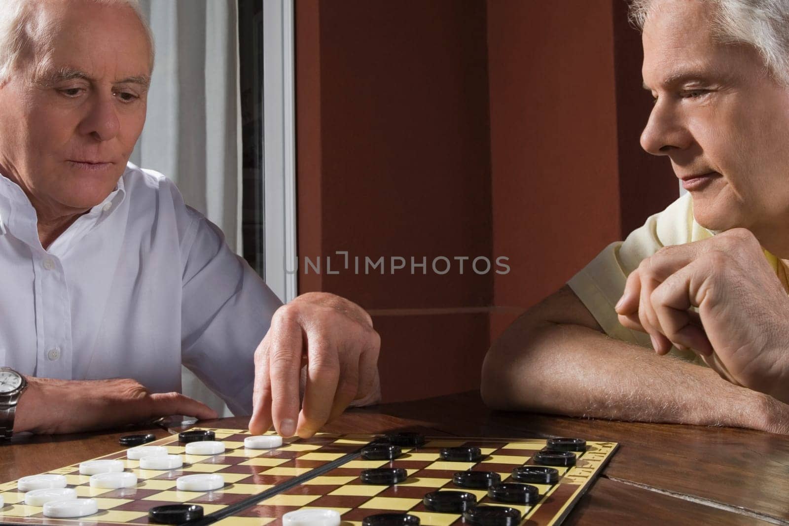 Two senior men playing checkers