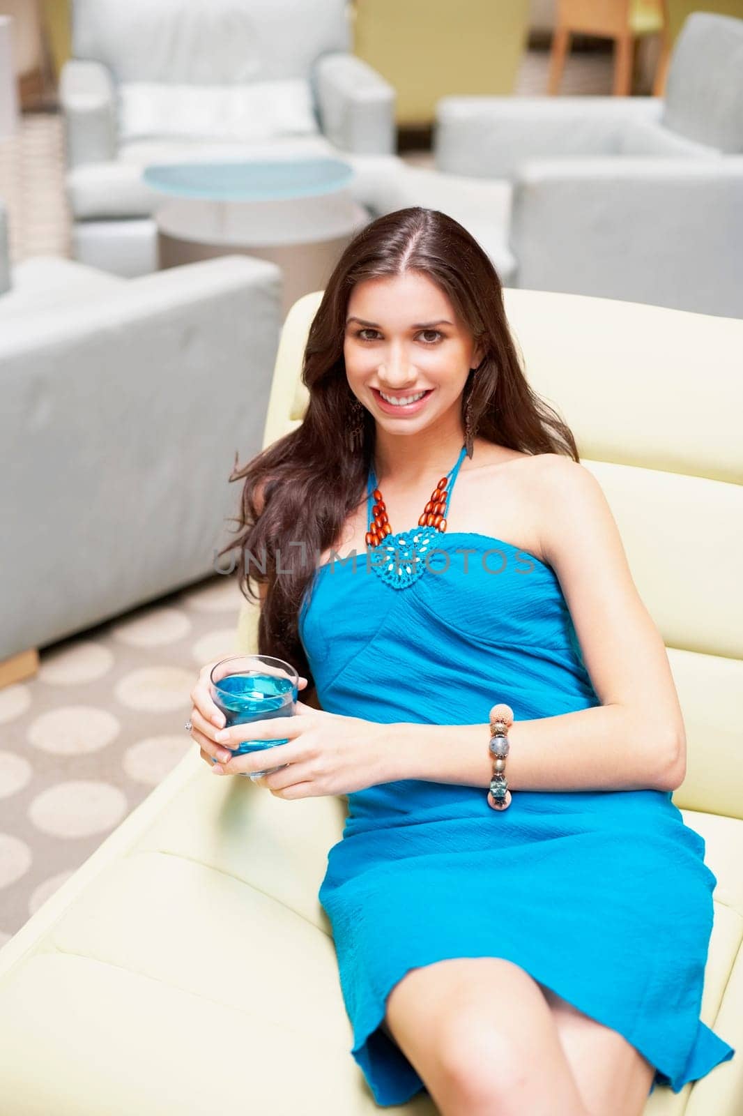 Portrait of a young woman reclining on a chair and holding a cocktail