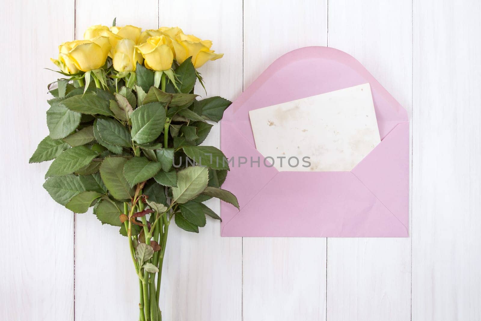 Yellow roses and love letter or note card with pink envelope