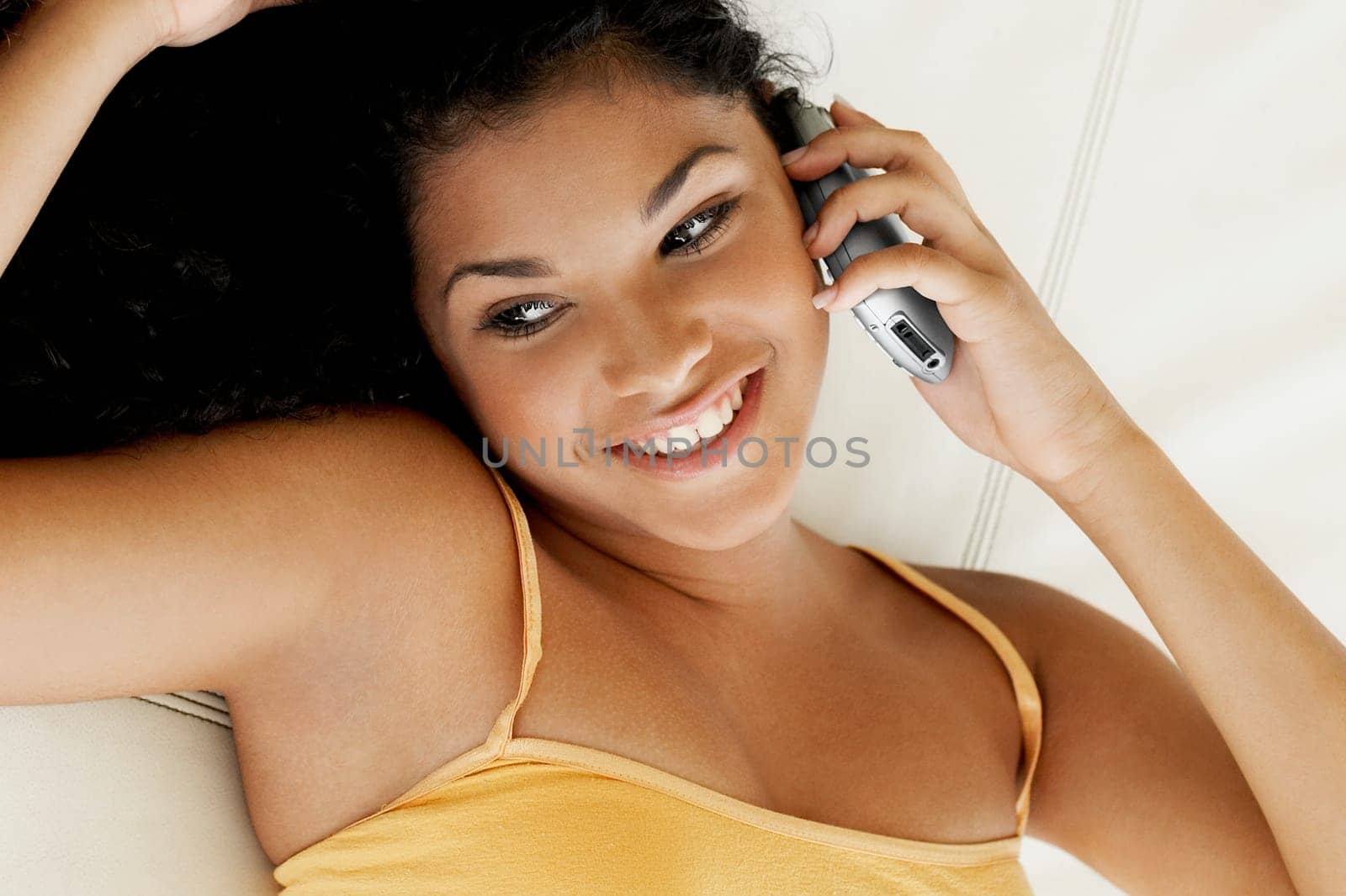 Close-up of a young woman lying on her back and talking on a mobile phone