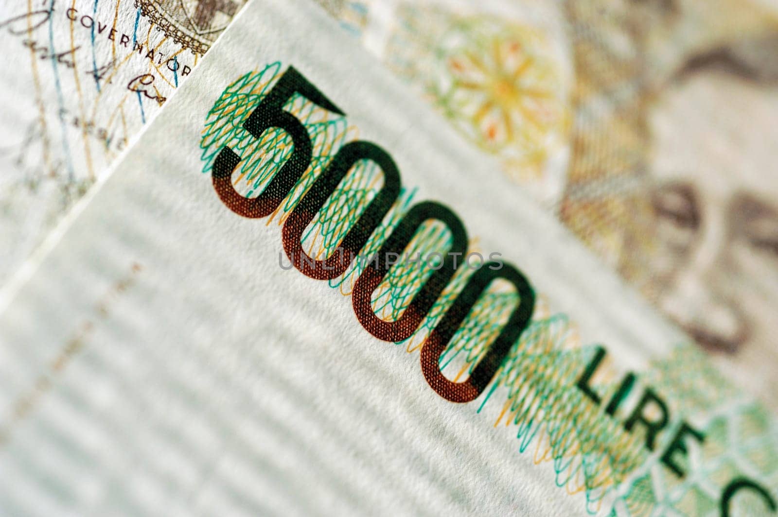 One 5000 Lire bank note on top of other currency, close-up