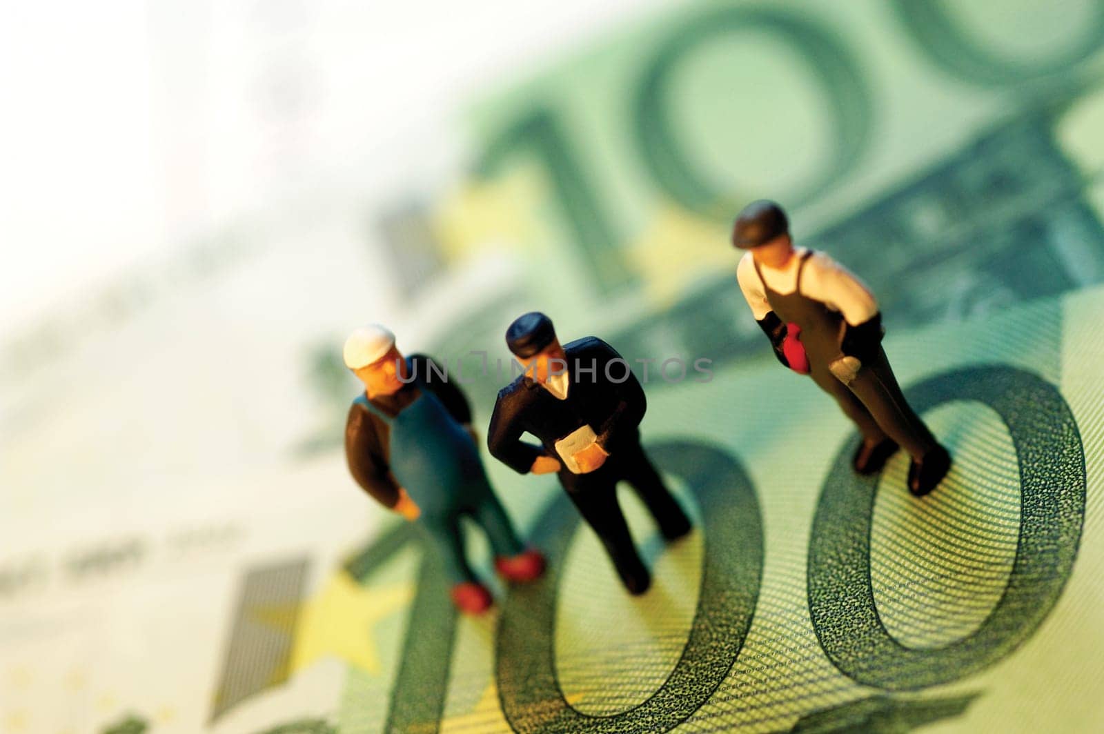 Three toy men standing on top of paper currency, close-up