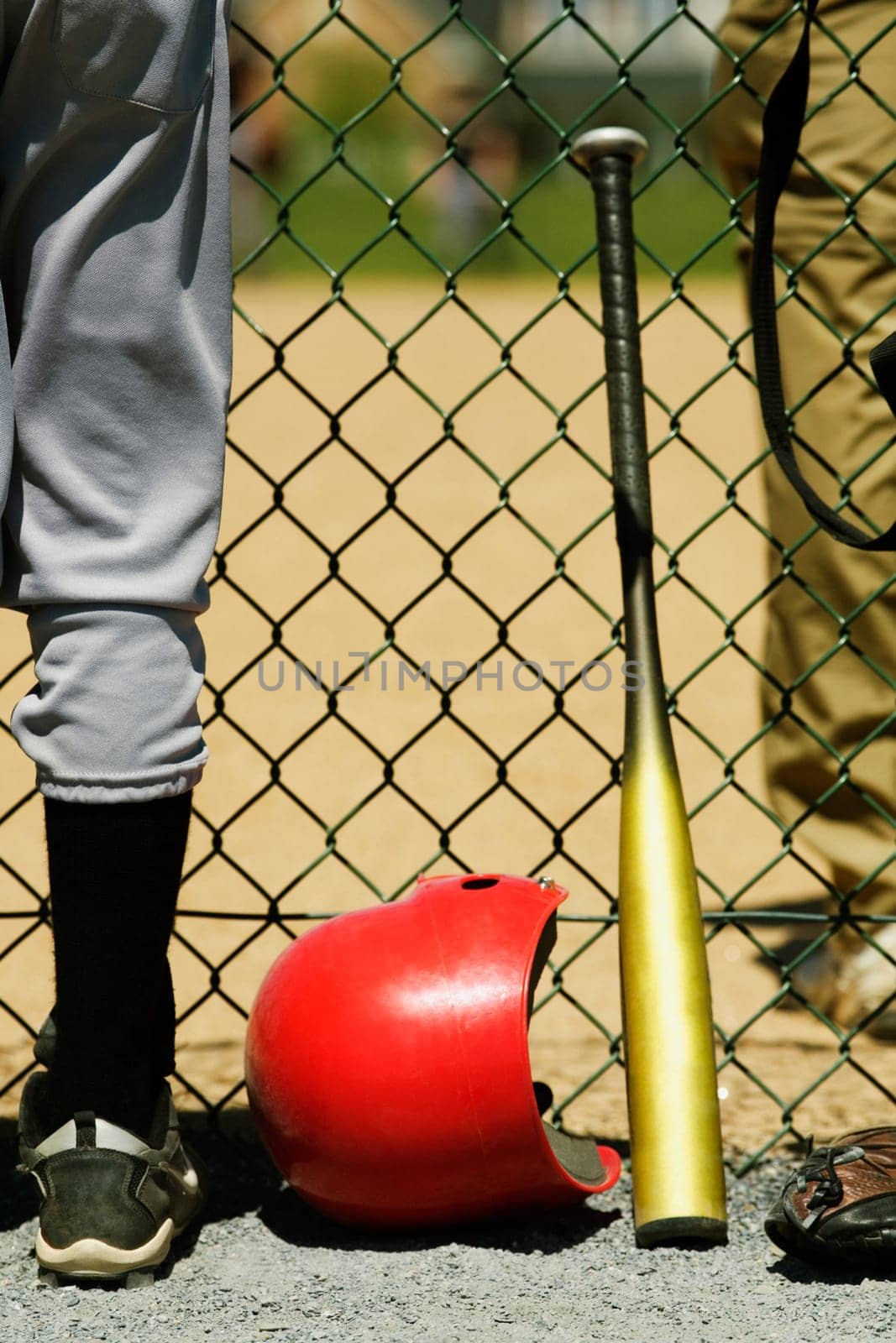Low section view of two boys standing on either sides of a chain-link fence