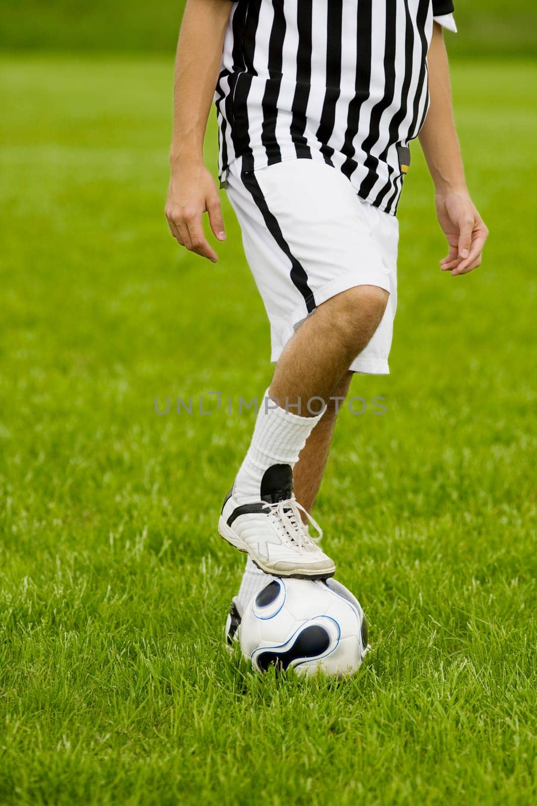 Low section view of a soccer player resting his foot on a soccer ball
