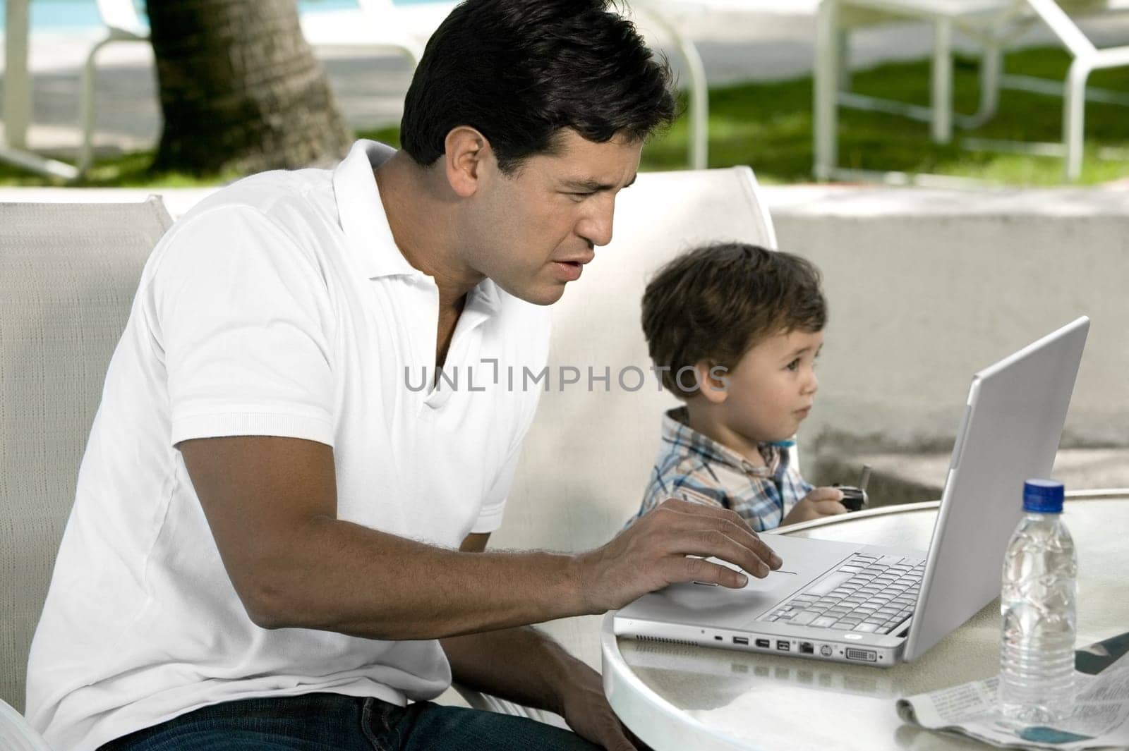 Side profile of a father working on a laptop with his son sitting beside him