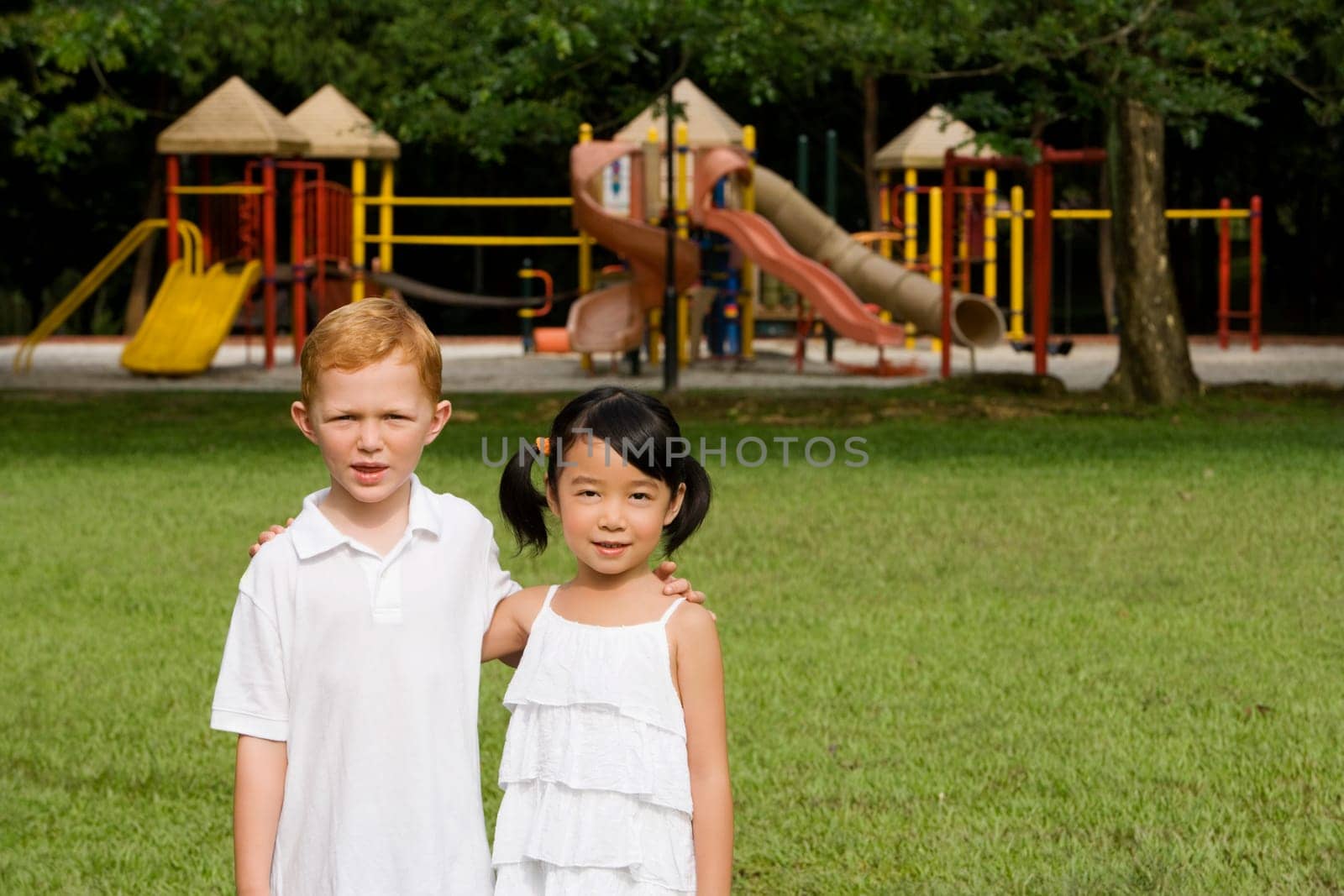 Portrait of a boy standing with a girl in a park