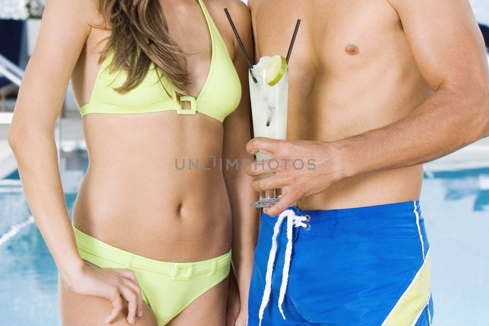 Mid section view of a man holding a glass of drink and standing with a woman