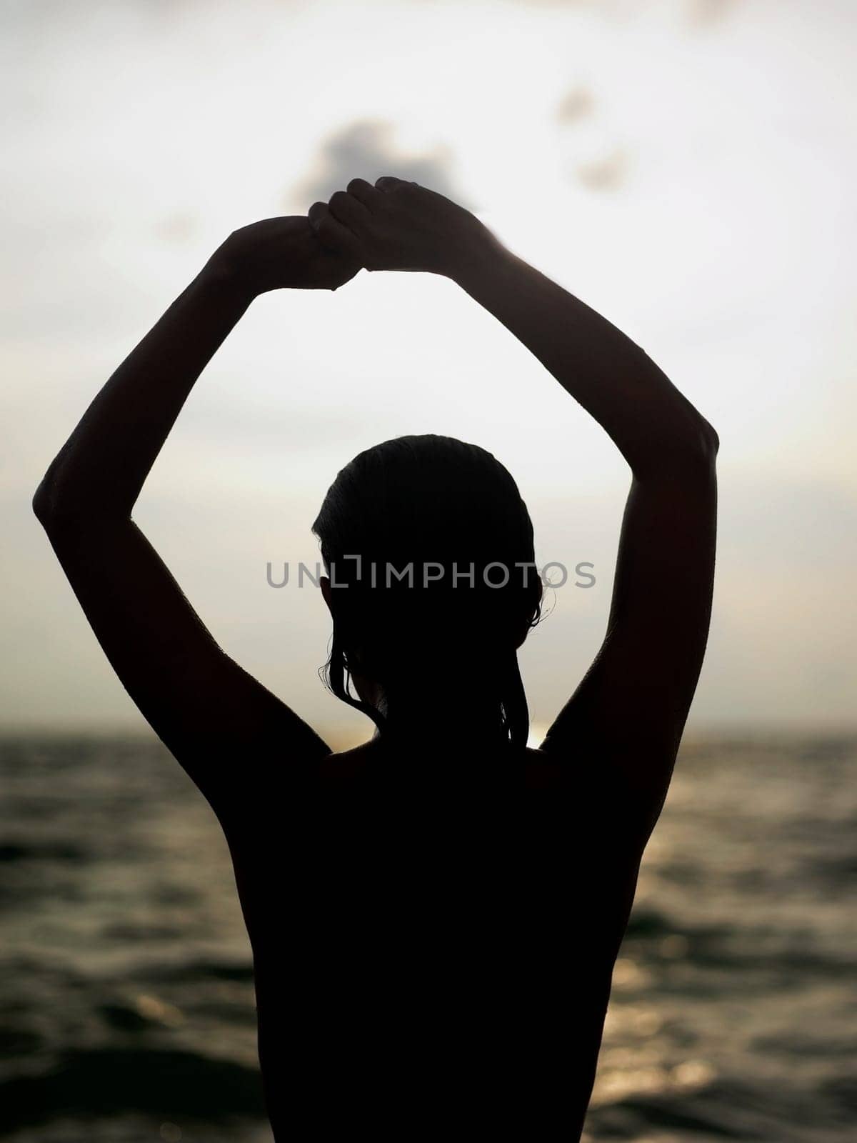 Silhouette of a young woman with her arms raised