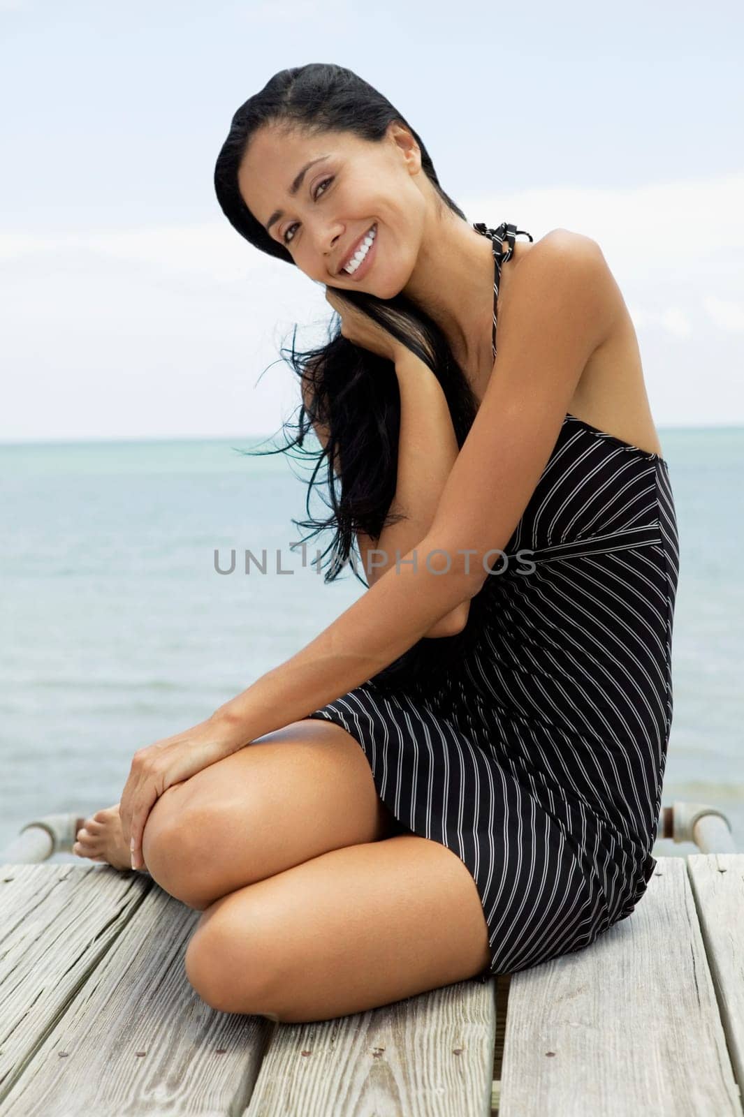 Portrait of a young woman sitting on a pier and smiling