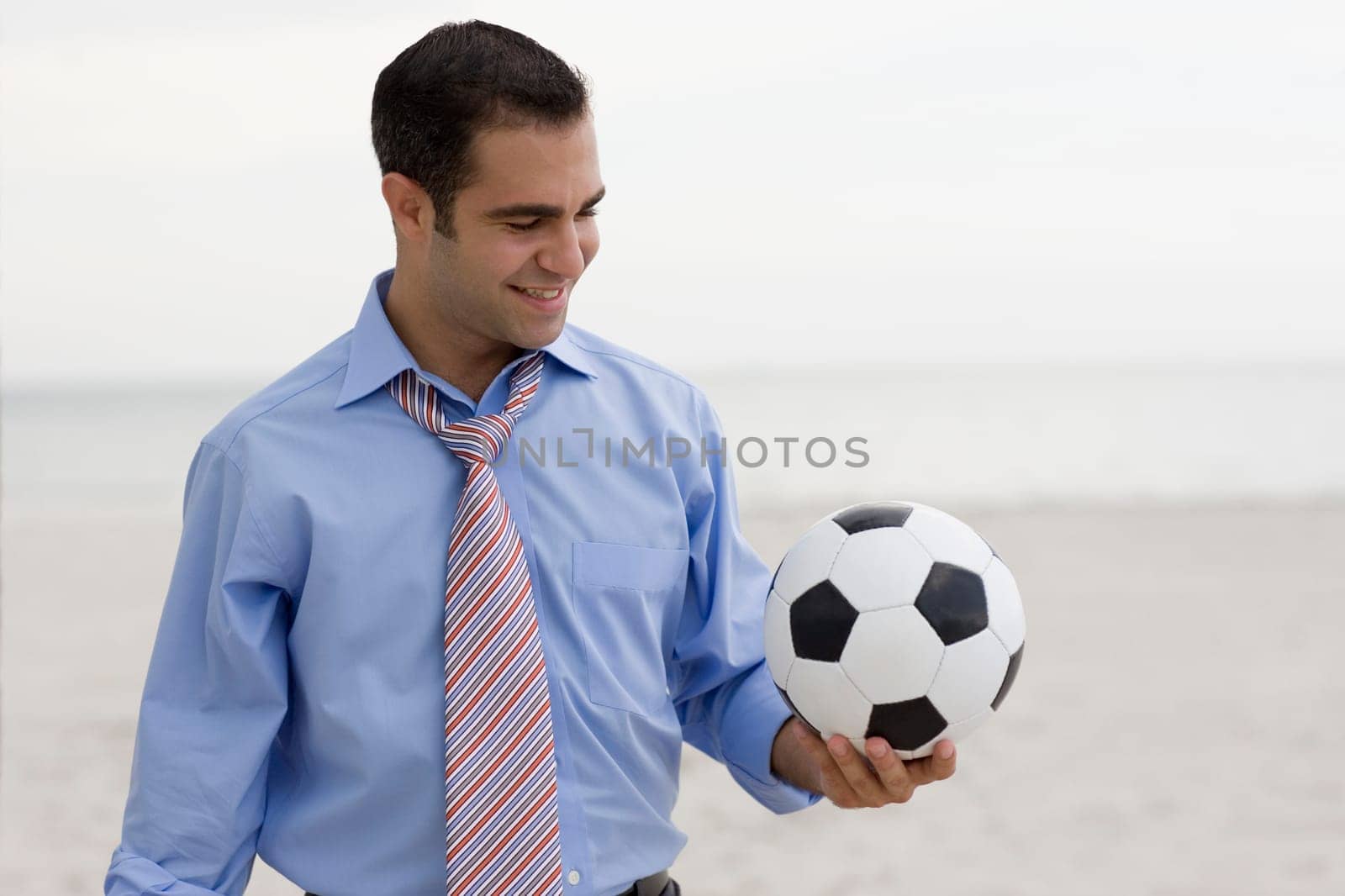 Close-up of a young man standing on the beach and holding a soccer ball