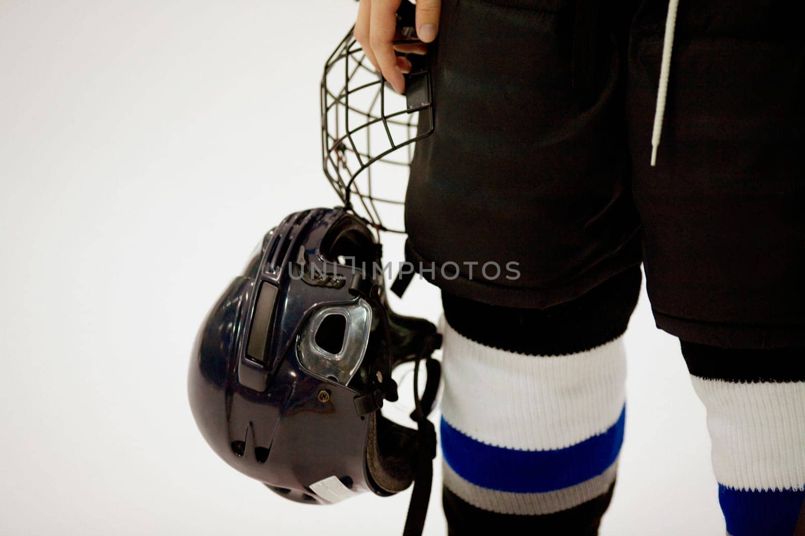 Mid section view of an ice hockey player holding a helmet