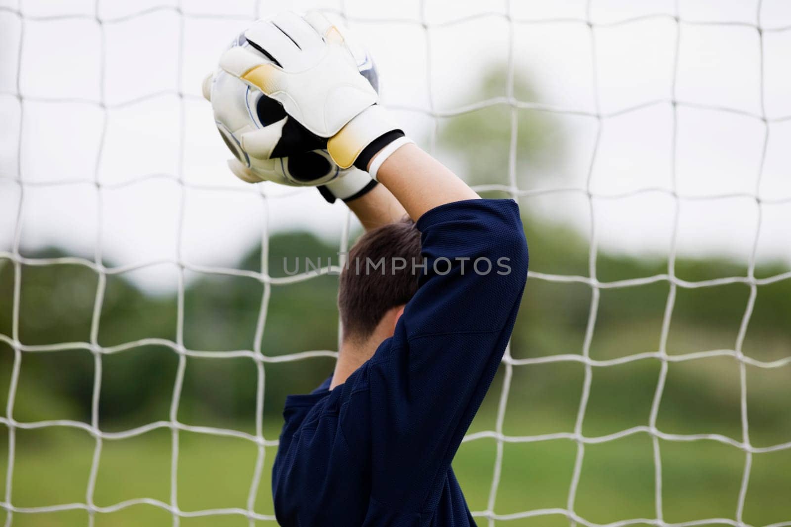 Side profile of a goalie holding a soccer ball over his head