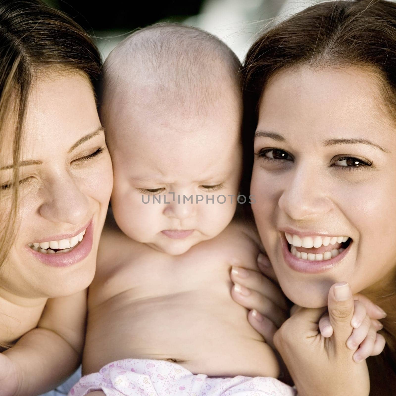 Close-up of two young women holding a baby girl