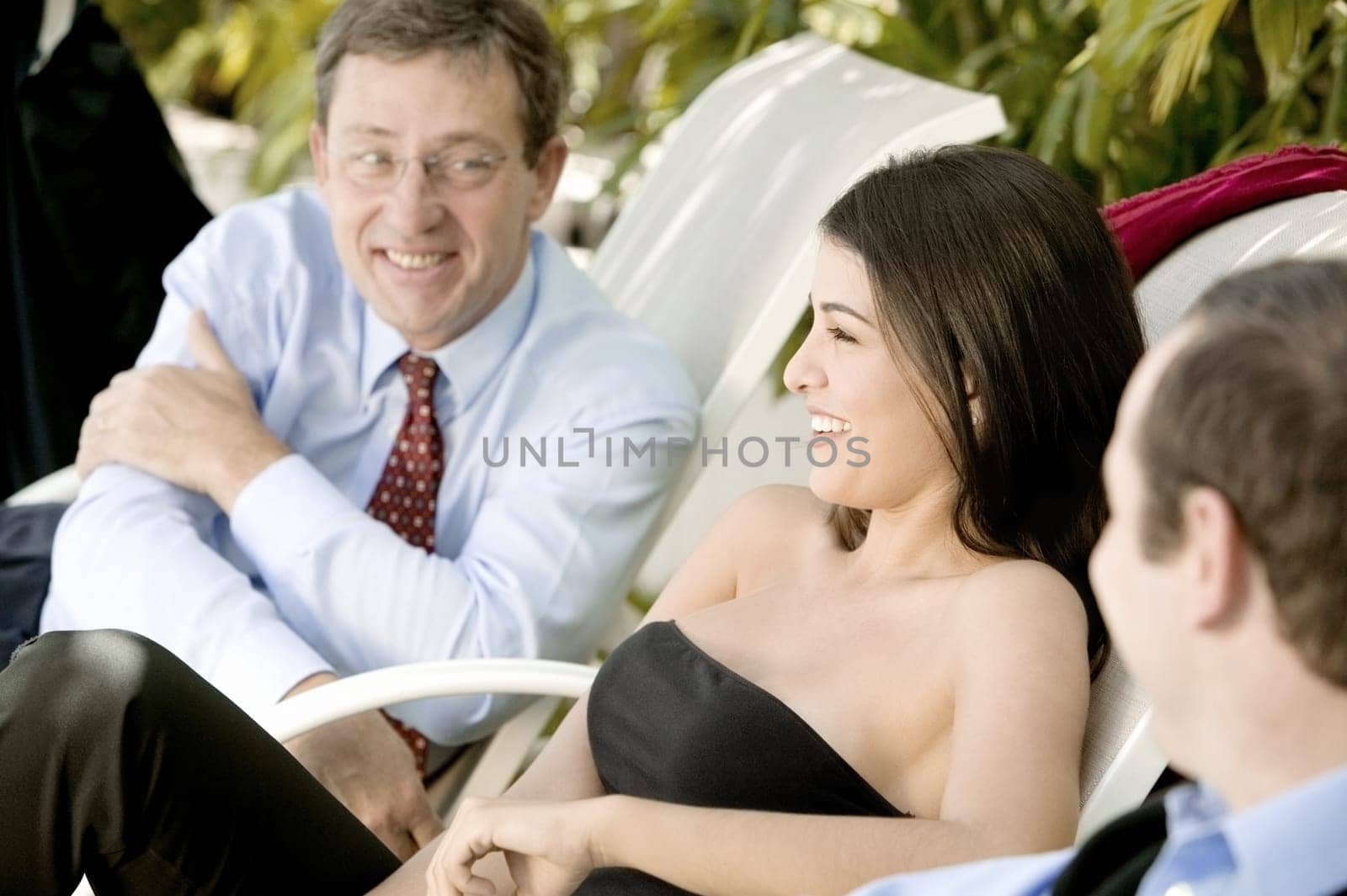 Two businessmen and a businesswoman sitting on lounge chairs