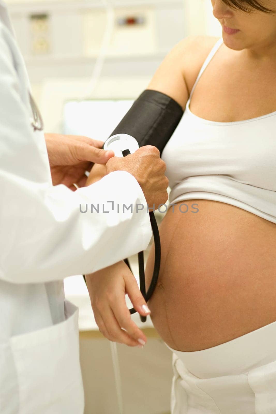 Close-up of a male doctor checking pregnant young womanŽs blood pressure