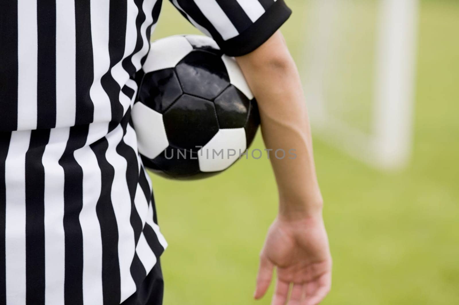 Mid section view of a referee with a soccer ball under his arm