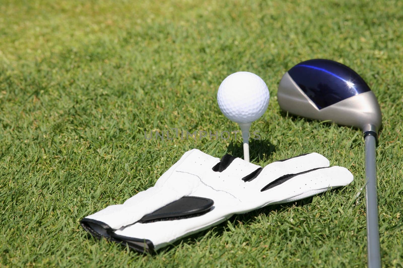 Close-up of a golf club near a golf ball and a golf glove