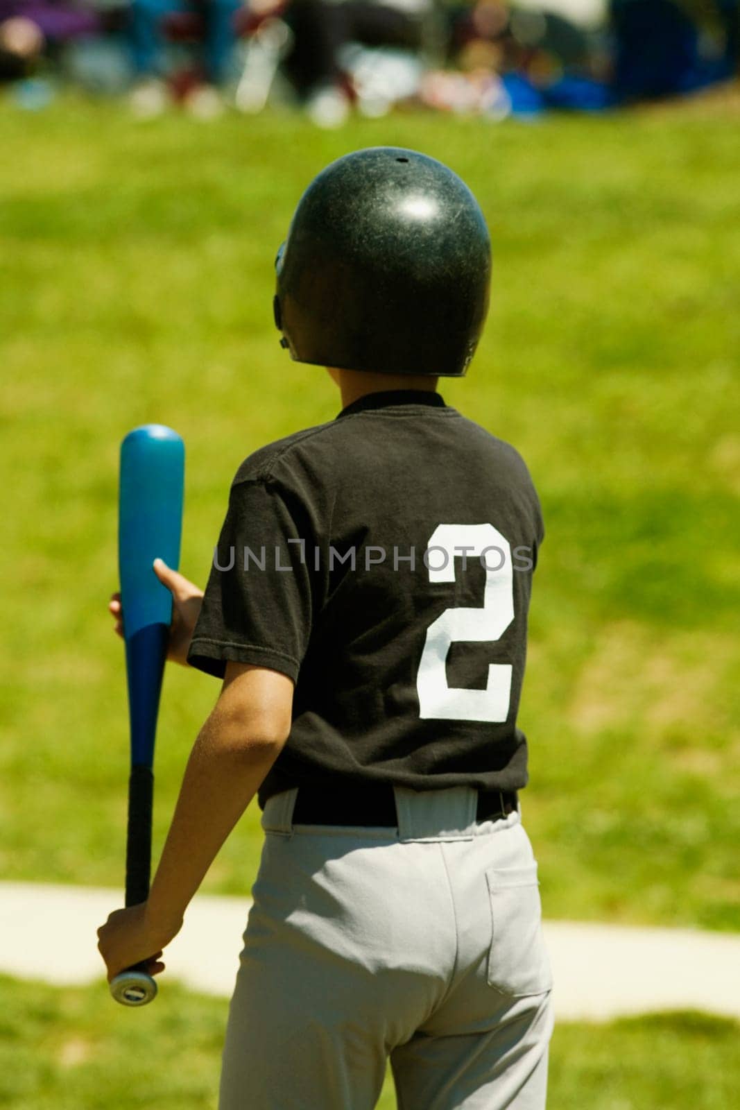Rear view of a baseball player holding a baseball bat
