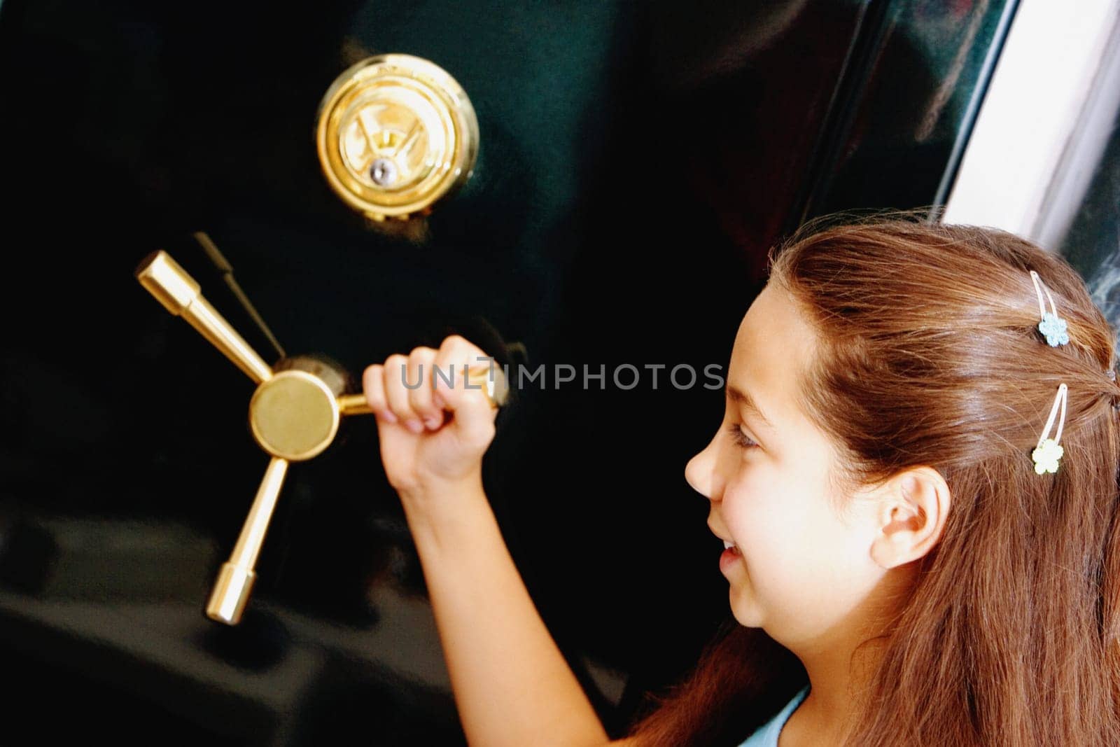 Side profile of a girl holding the handle of a safe