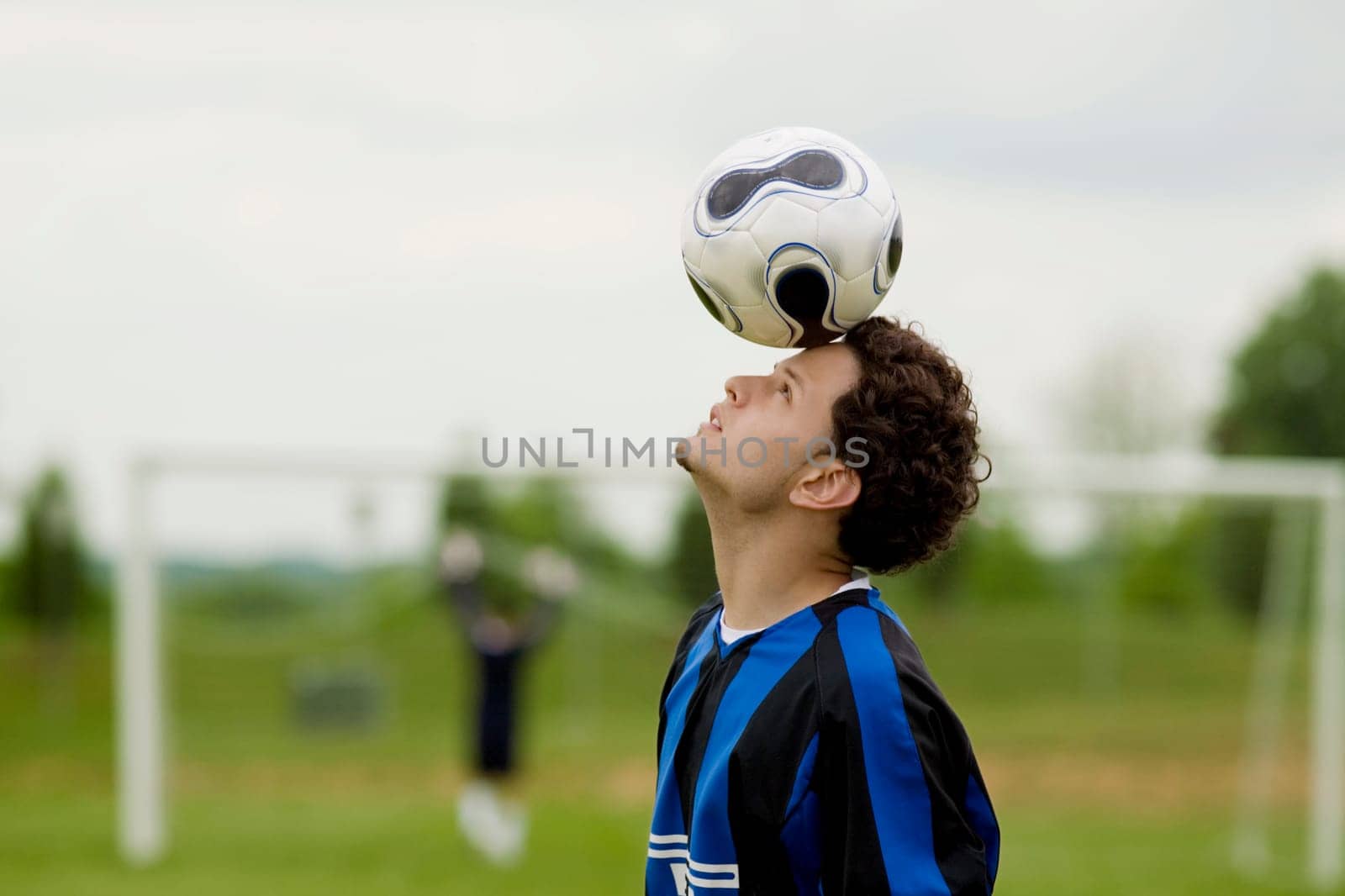 Side profile of a soccer player balancing a soccer ball on his forehead