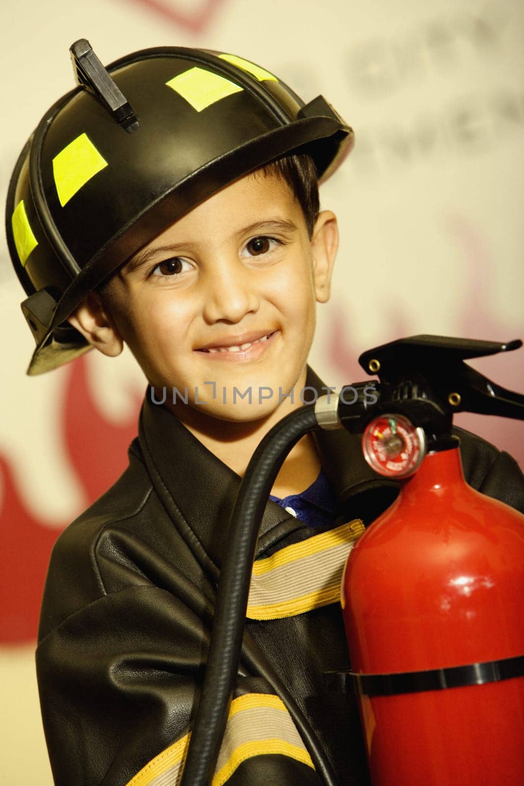 Portrait of a boy dressed as a firefighter and holding a fire extinguisher