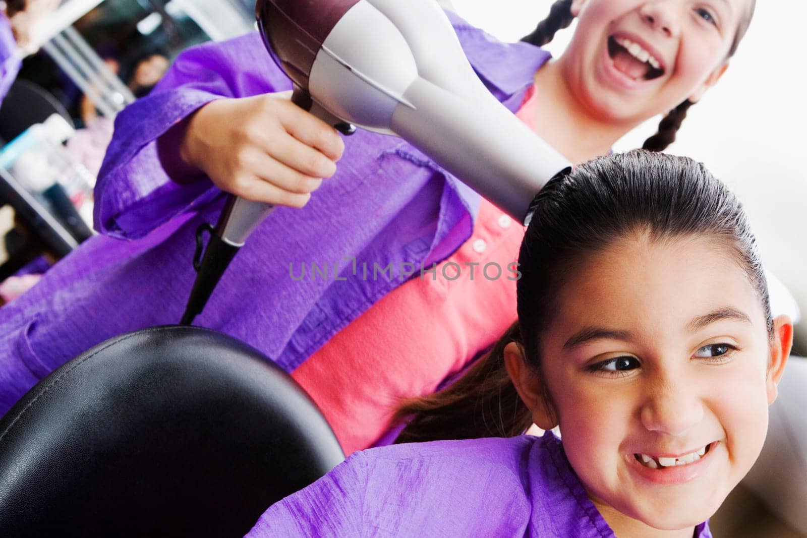 Close-up of a girl using a hair dryer on her sister