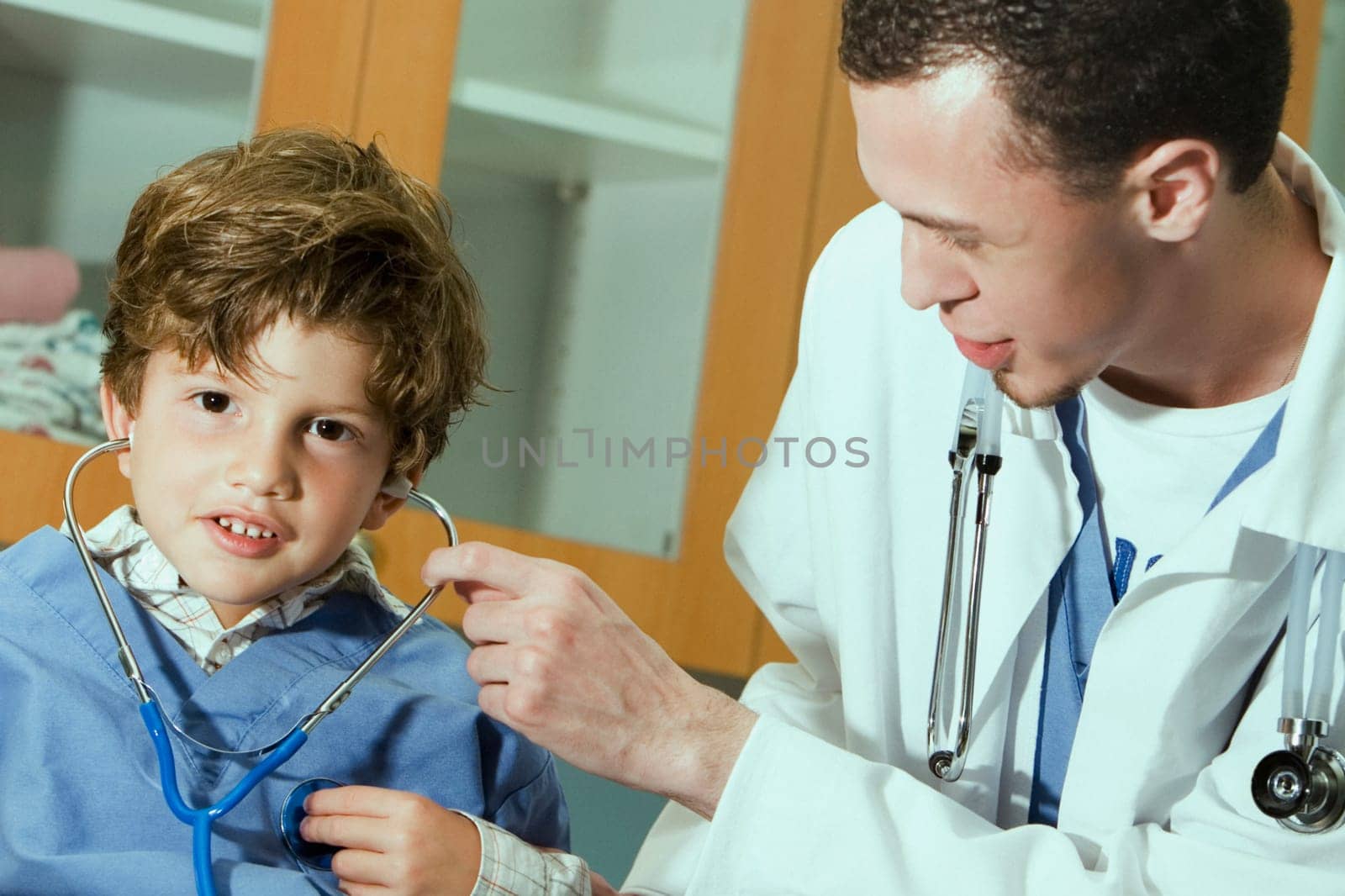 Male doctor putting a stethoscope on the ears of a boy