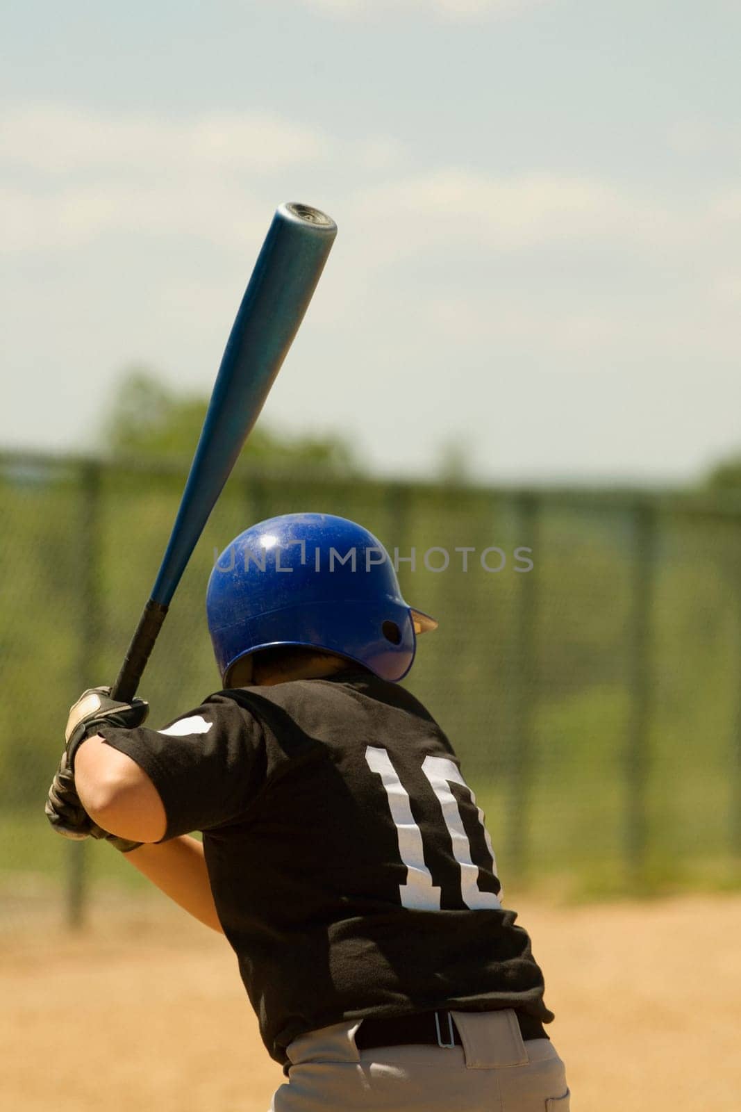 Rear view of a baseball player swinging a baseball bat