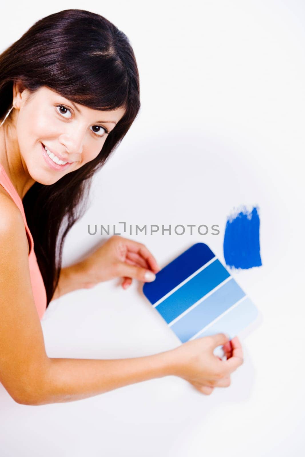 Portrait of a young woman holding a color swatch against a wall