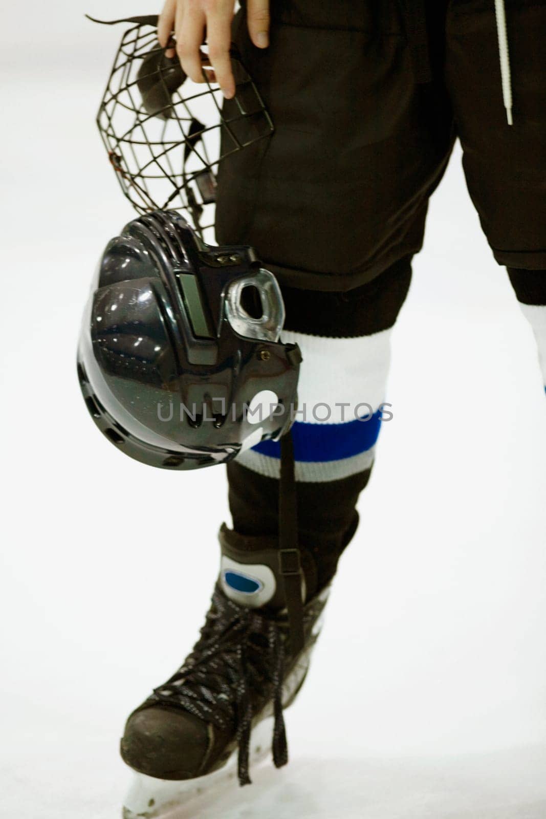 Low section view of an ice hockey player holding a helmet