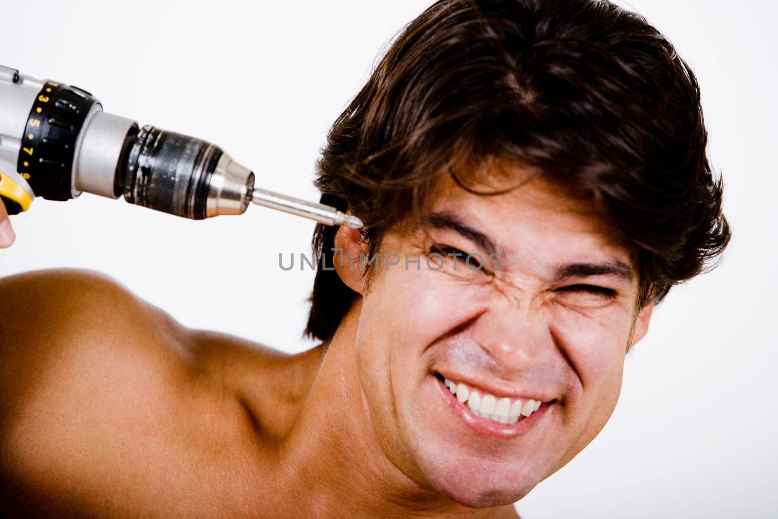 Mid adult man holding a drill machine against his head