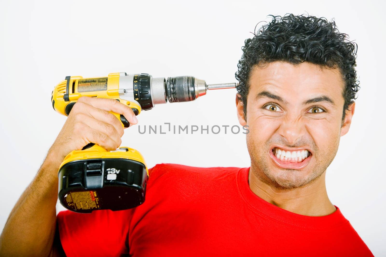 Portrait of a young man holding a drill machine against his head