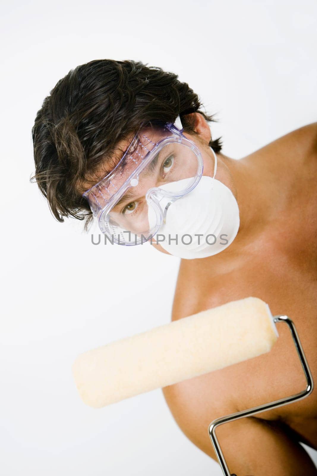 Portrait of a mid adult man wearing a pollution mask with a protective eyewear and holding a paint roller