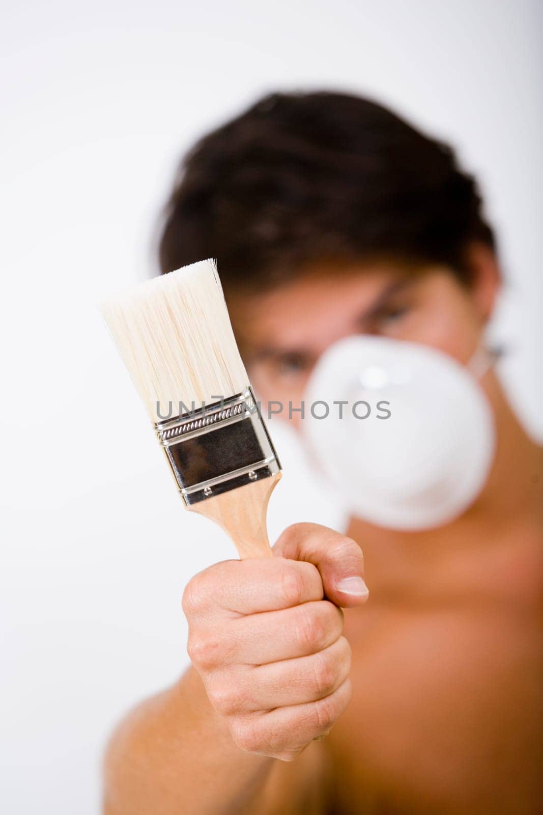 Portrait of a mid adult man wearing a pollution mask and holding a paintbrush