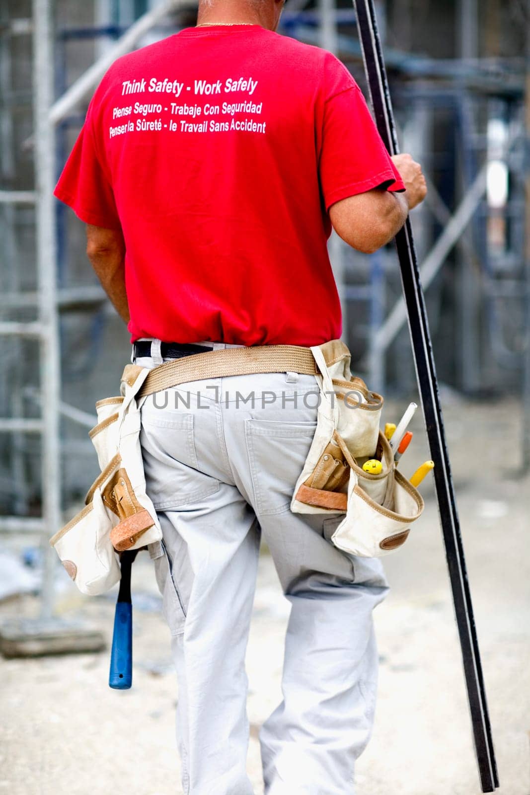 Rear view of a male architect walking and holding a spirit level