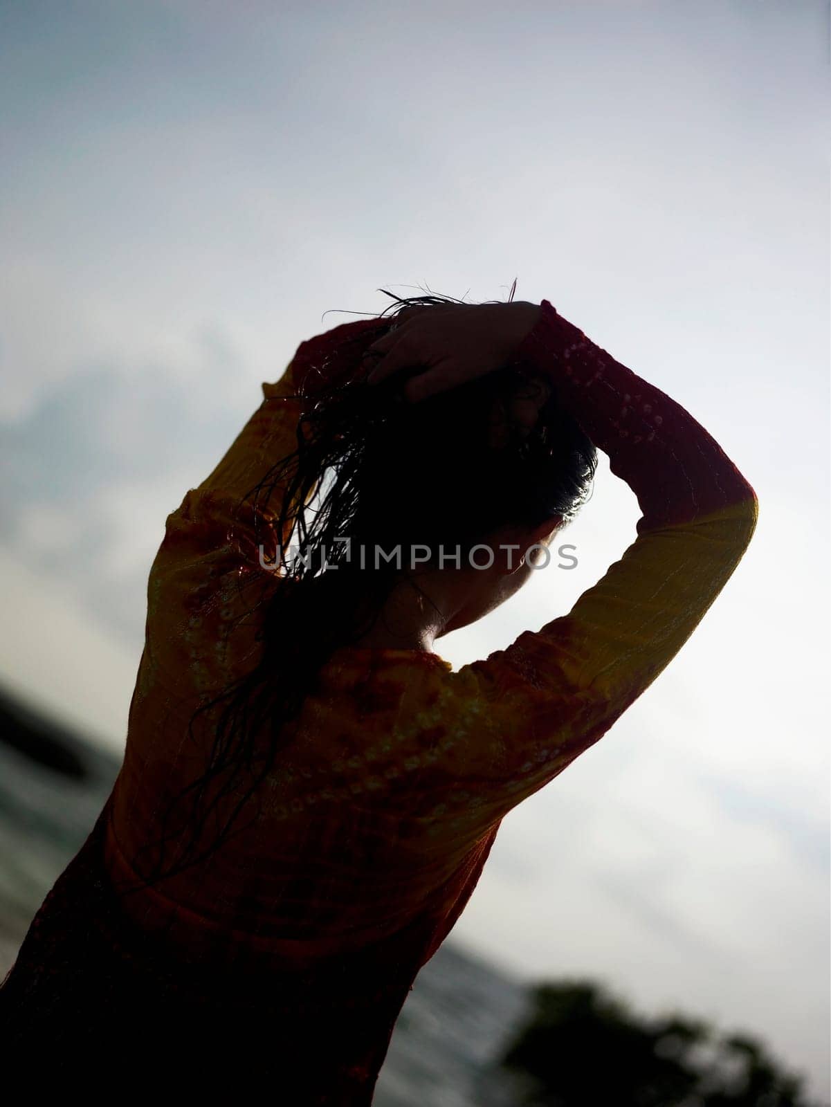 Silhouette of a young woman with her hands on her head