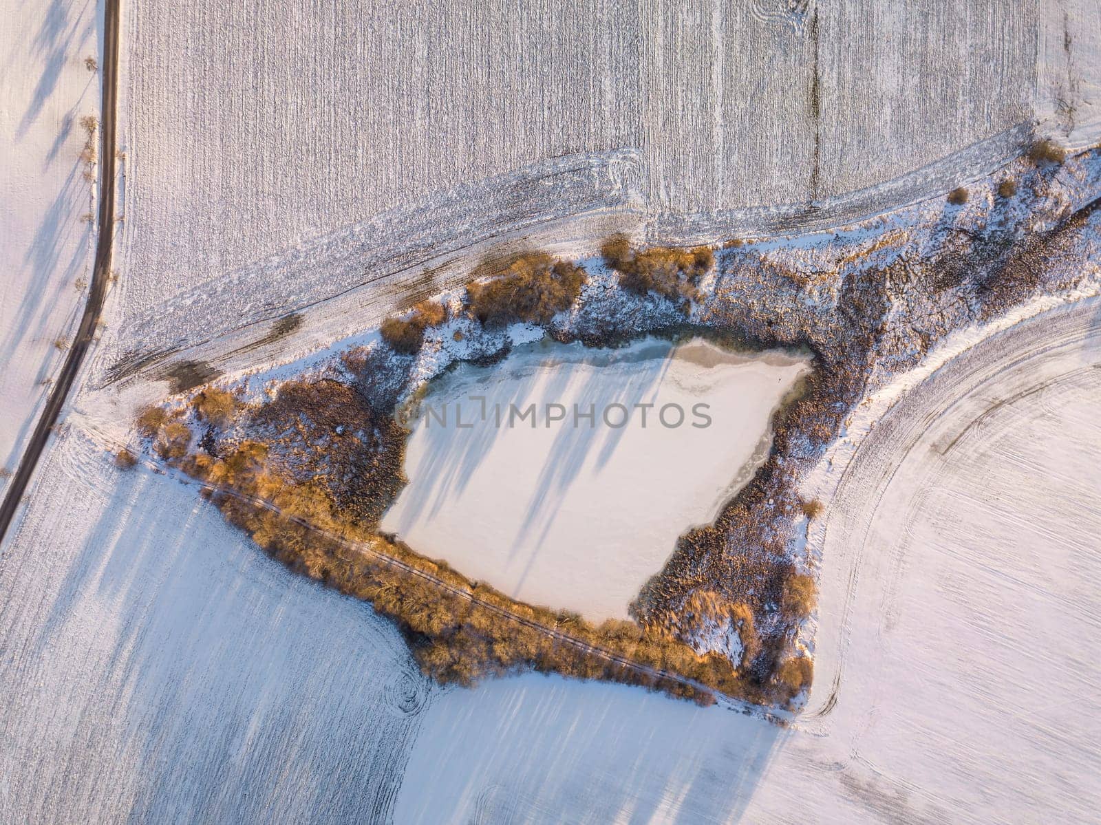 Aerial bird view of beautiful winter landscape with frozen pond covered with snow. Central european countryside. Czech Republic, Vysocina Highland region, Europe