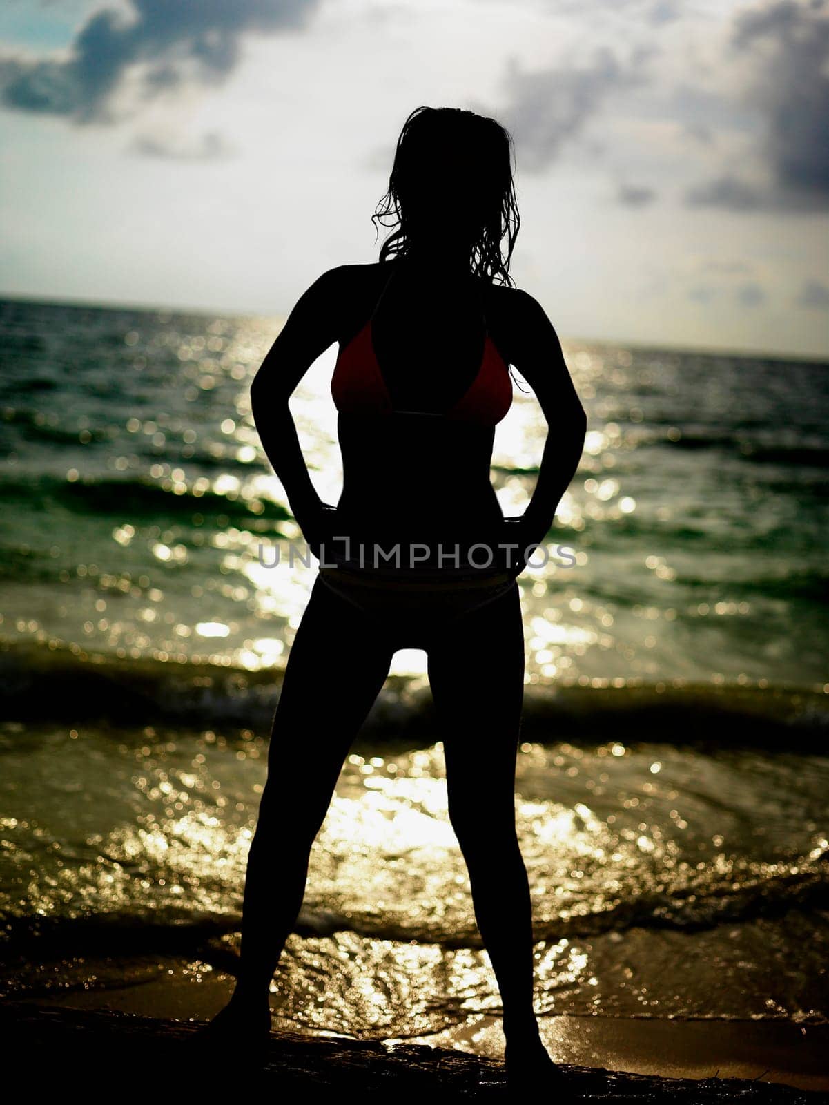 Silhouette of a young woman standing on the beach