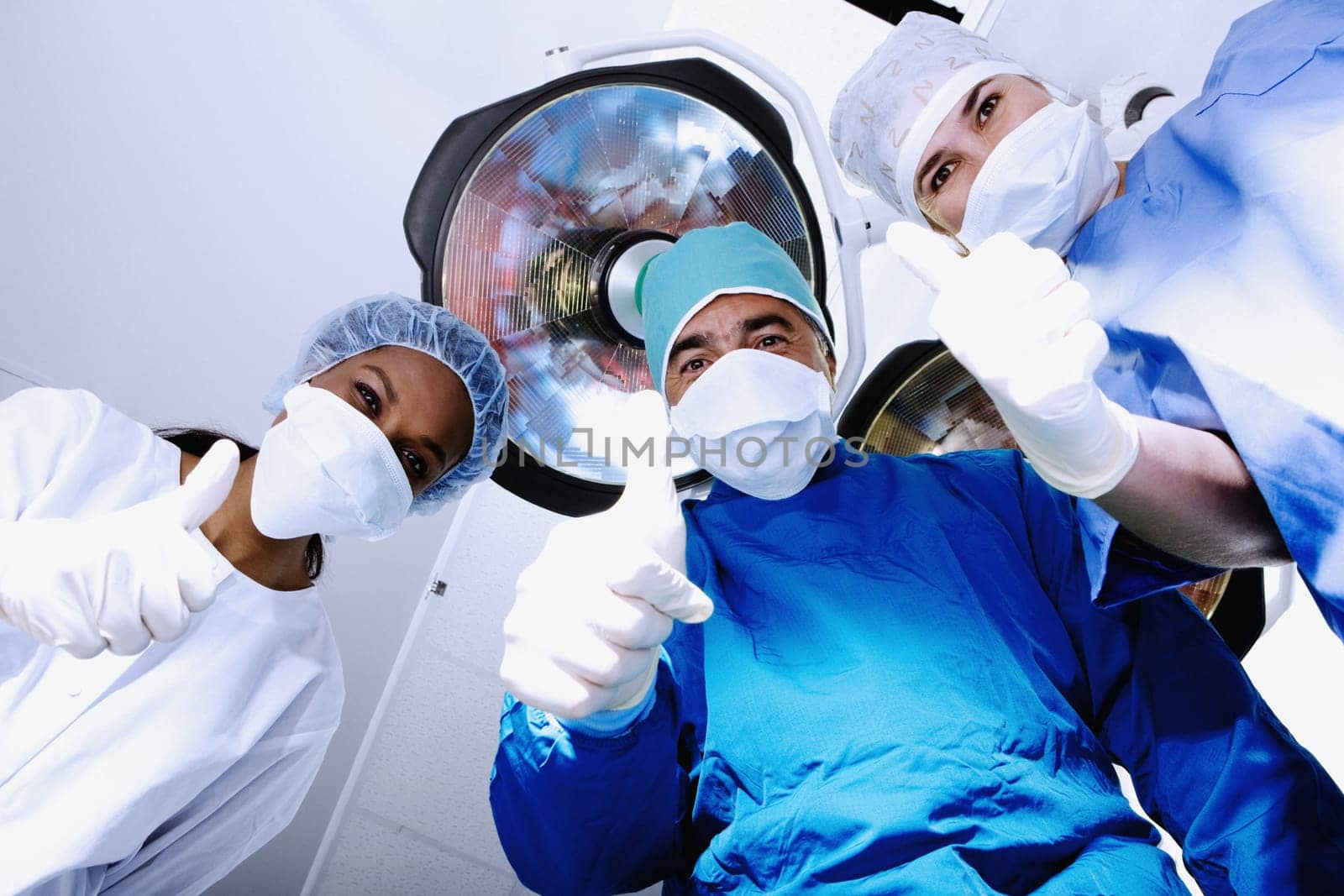 Male surgeon and two female surgeons making Thumbs Up sign