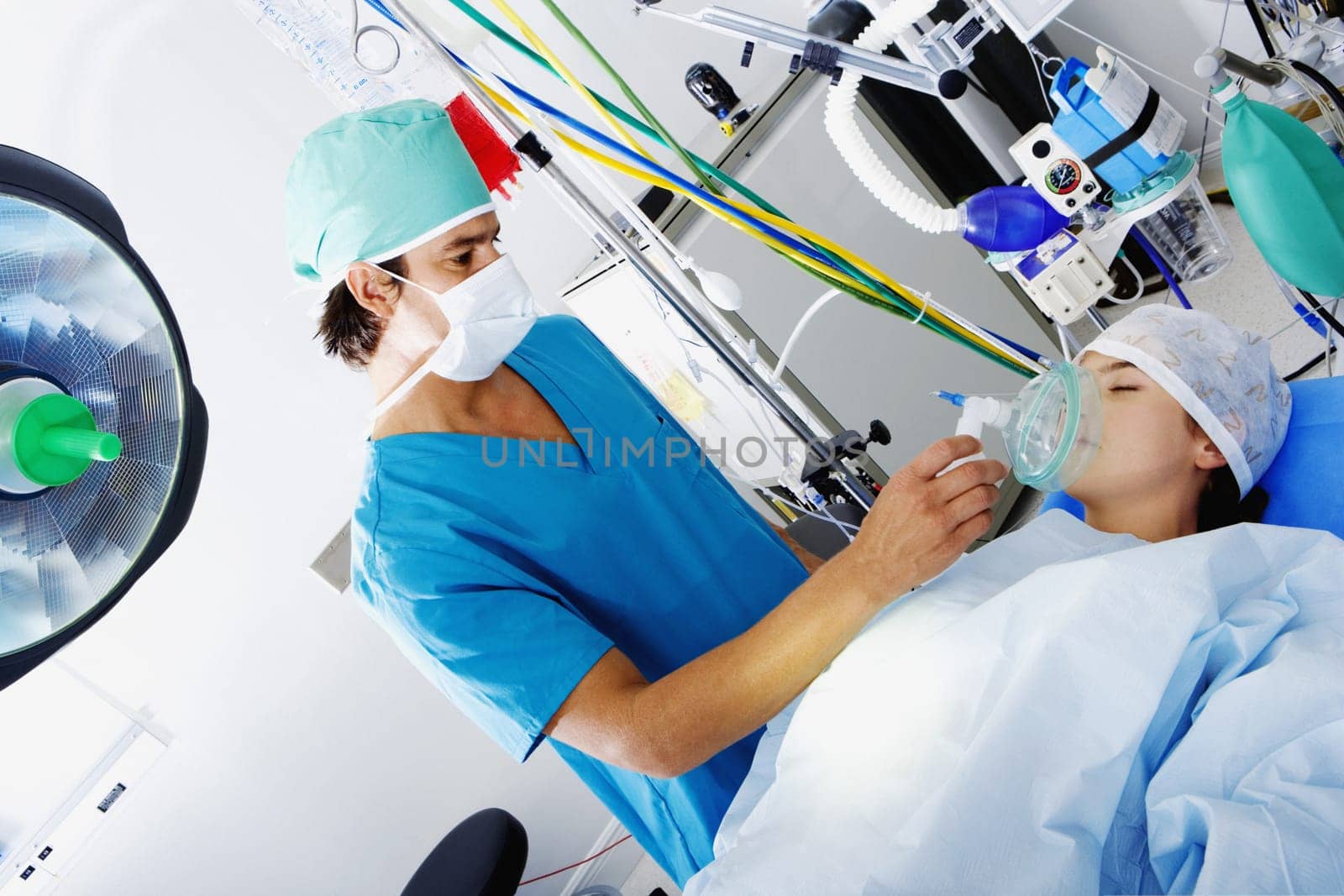 Male surgeon putting an oxygen mask on the mouth of a female patient