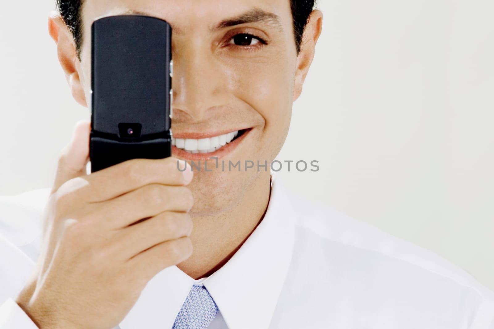 Portrait of a businessman covering his eye with a mobile phone