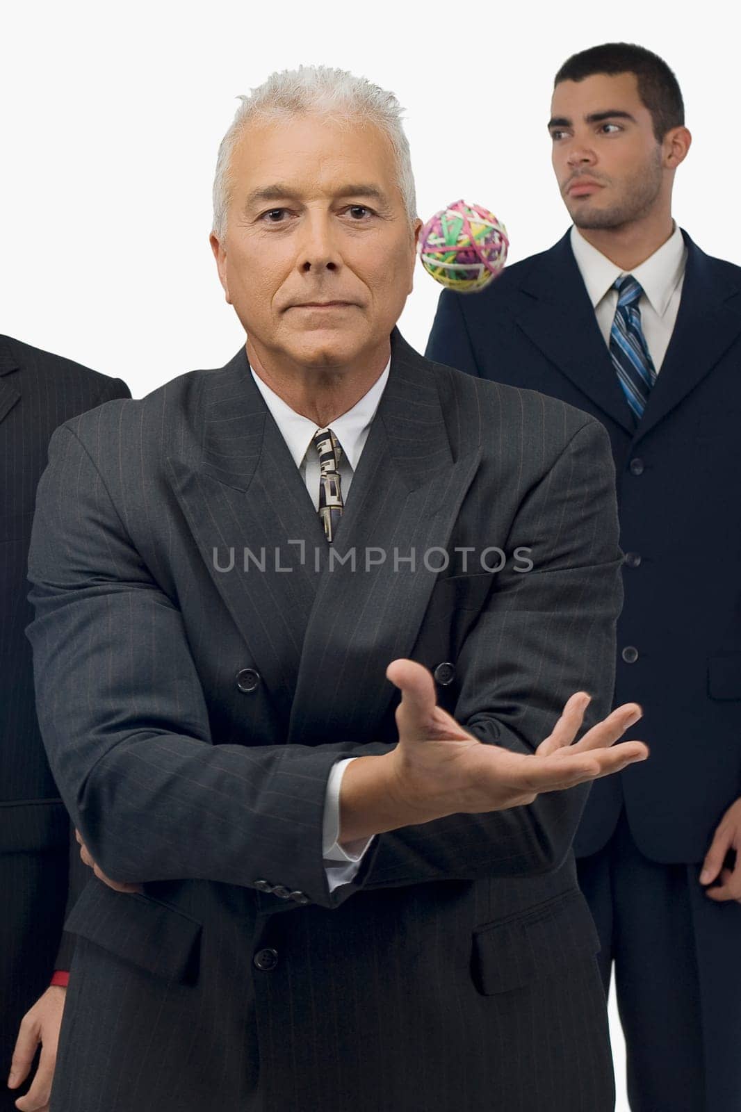 Businessman catching a rubber band ball with two businessmen standing behind him