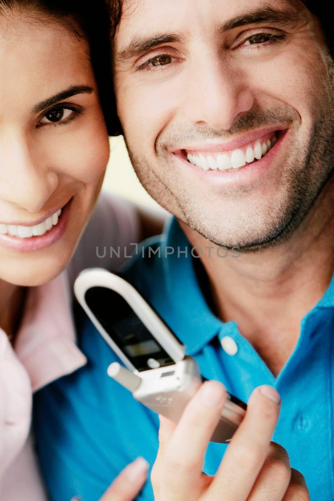Portrait of a young man holding a mobile phone and smiling with a young woman