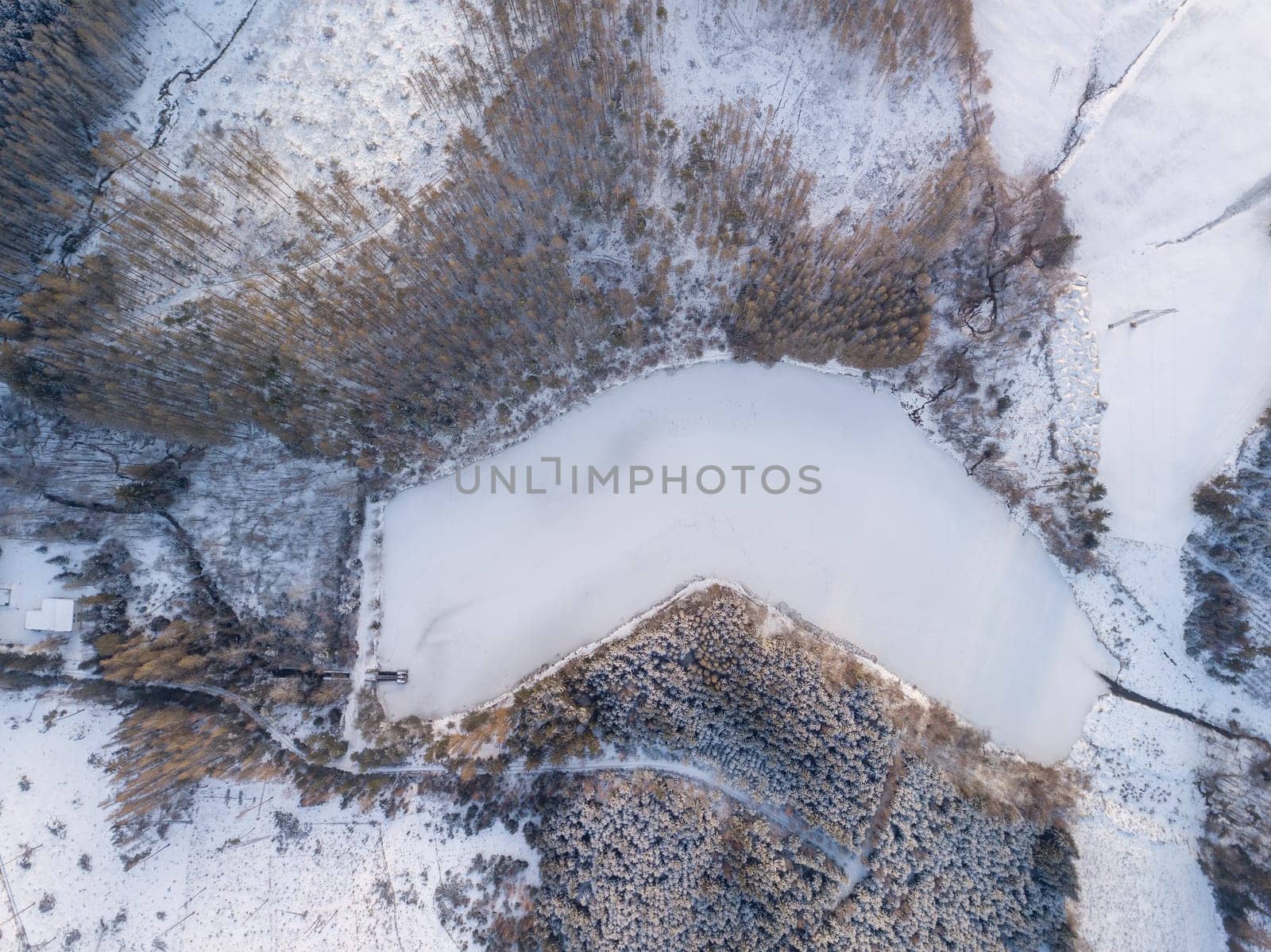 Aerial bird eye view of beautiful winter landscape with frozen water reservoir situated in forest covered with snow. European countryside. Czech Republic, Vysocina Highland region, Europe